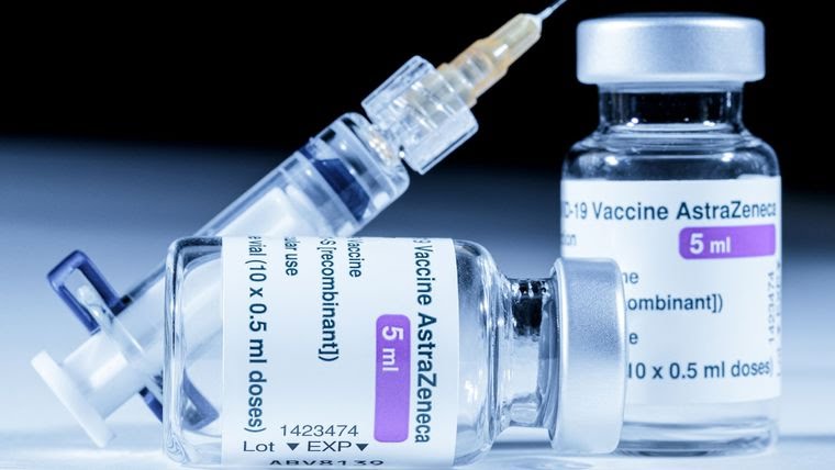 Deux flacons (l'un debout et l'autre couché) de vaccin AstraZeneca COVID-19 avec une seringue remplie.